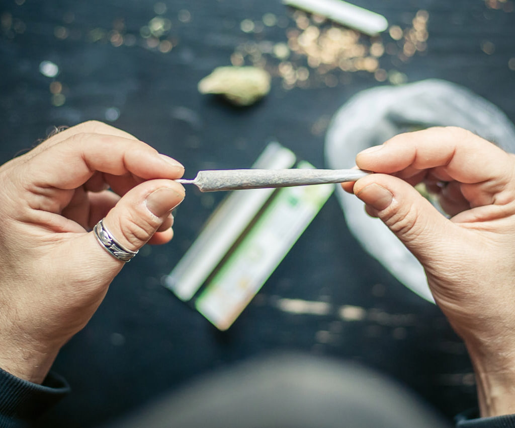 Close-up of hands skillfully rolling a cannabis joint, showcasing the art of cannabis preparation